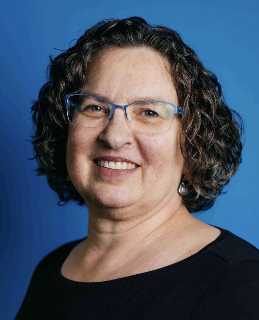 Portrait of Laura Pierce, a white woman in her 50s with curly brown hair wearing a black shirt